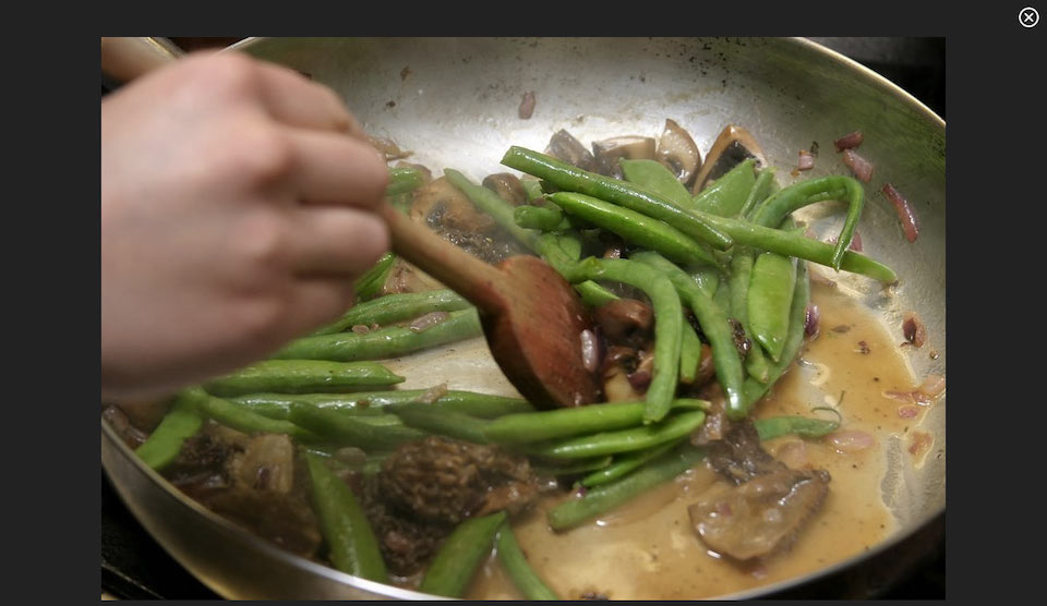 Screenshot of video, a hand cooking green beans in sauce